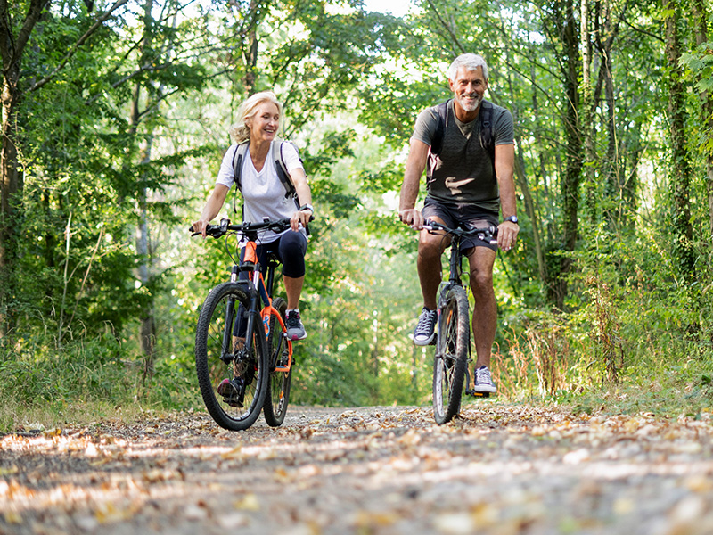 Spry Finance switch to Lifetime Loan - a retired couple cycling bikes in a wood