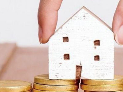 Spry Finance switch to Lifetime Loan - hand holding a small wooden house on top of coins